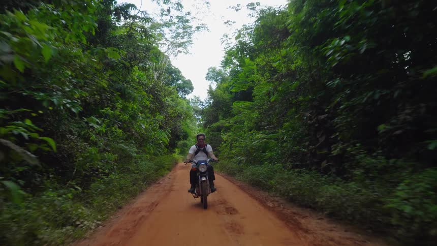 A man is riding a motorcycle in a wooded area