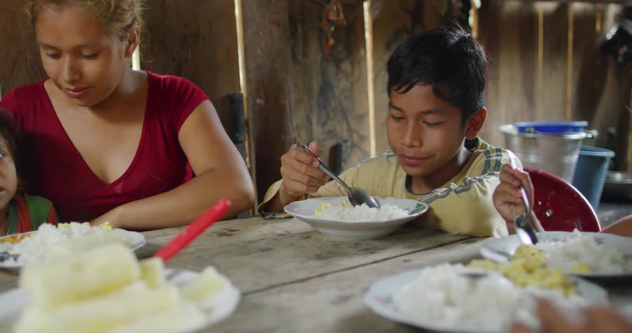 People sitting at a table eating rice with a spoon