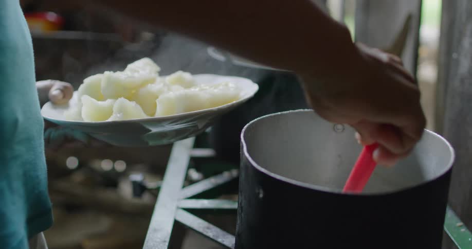 A man scoops food out of a pot and puts it in a bowl