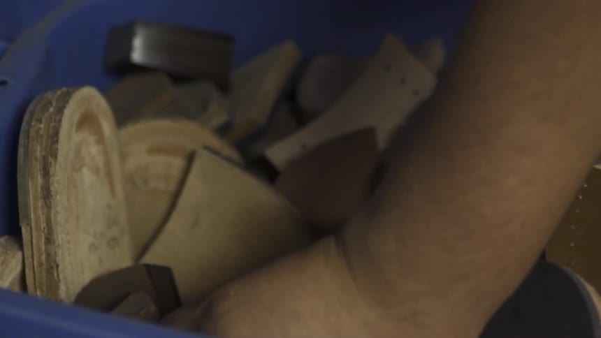 A hand reaches into a bin full of shoe heels and pulls some out