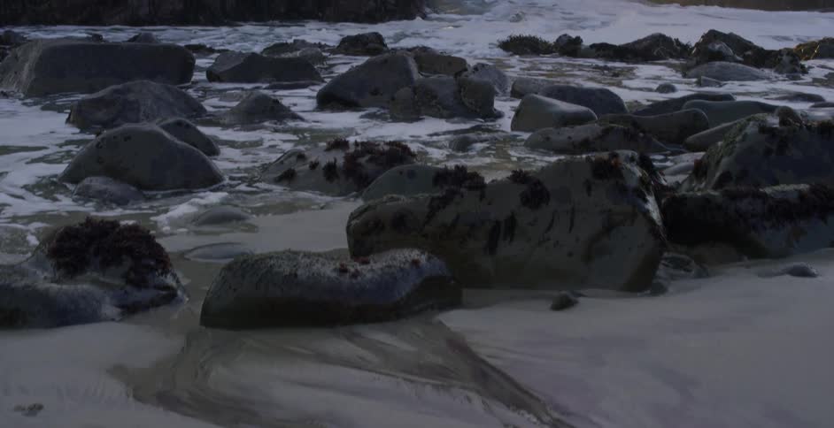 Waves crashing over rocks and towards the shore