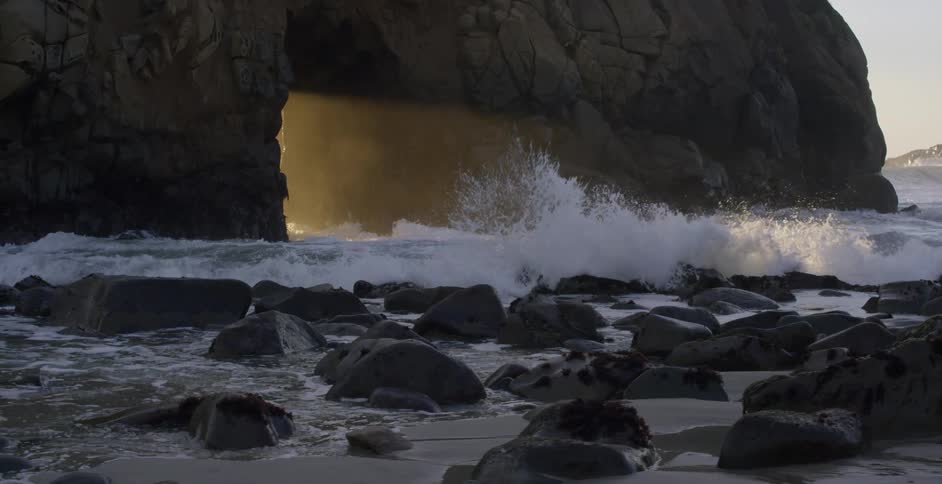 Waves crashing on rocks at the base of a canyon