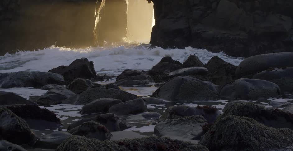 Waves crashing between rocks as they reach the shore