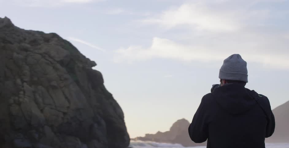 A photographer takes pictures as waves crash towards the shore