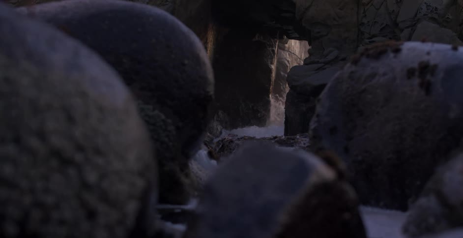 Sunset sunlight filtering through the opening on a rock wall in a beach