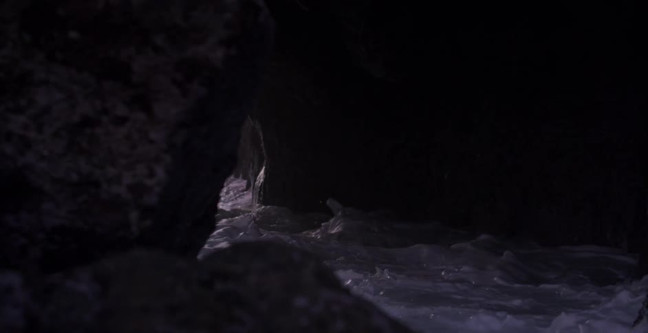 A cave entrance near the coast with waves of water entering