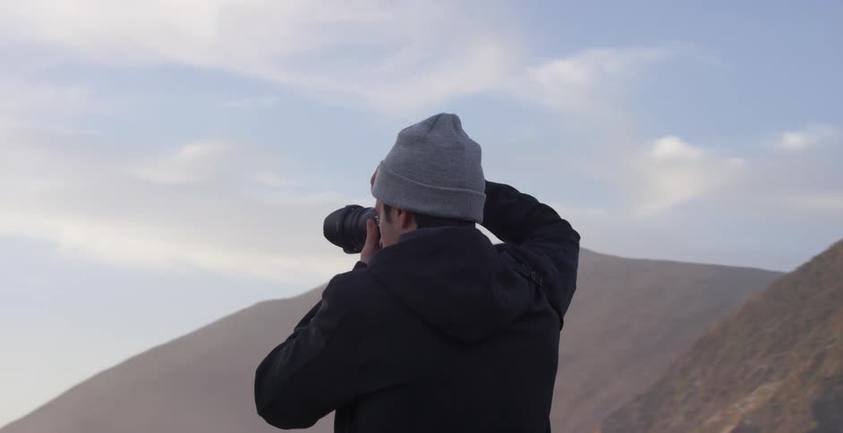 A group of people take pictures of a river flowing by a canyon
