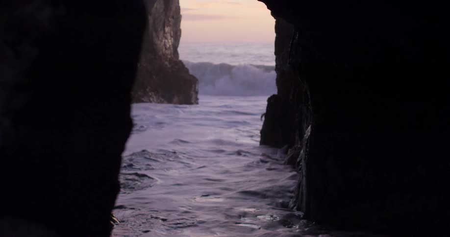 A cave close to the coast with the ocean waves and the sky in the background
