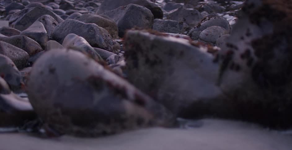 A beach with rocks and sand with waves of water