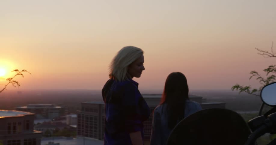 Three people look over the city at sunrise