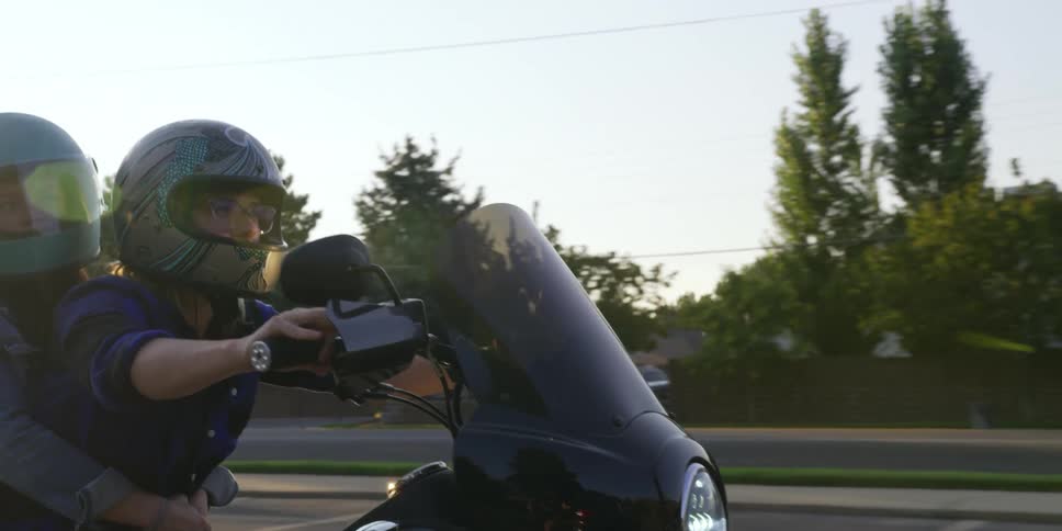 People riding on a motorcycle down a neighborhood street