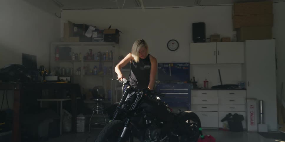 A woman works on a motorcycle in a garage