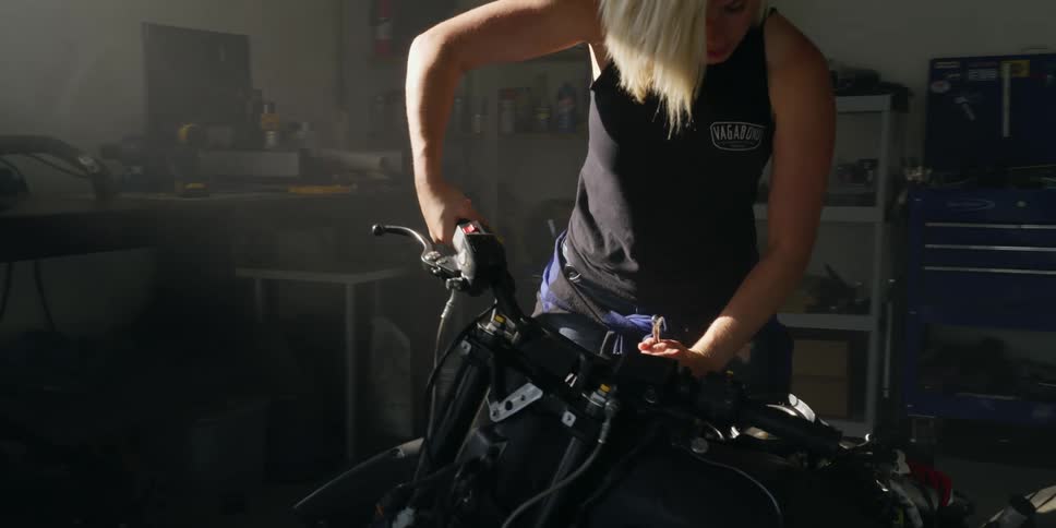 A woman works on a motorcycle in her garage