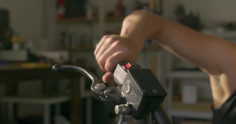 A woman twists the throttle of her motorcycle in a garage