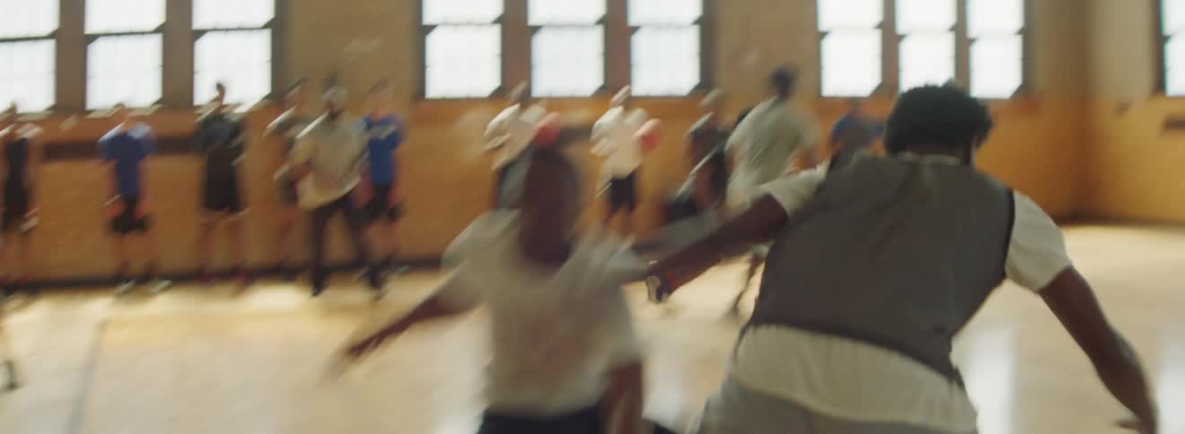 Group of teens practice basketball on an indoor court