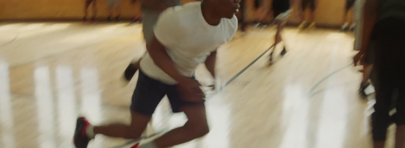 Teens on a basketball court in the school gym have to be separated for fighting after one boy is knocked down