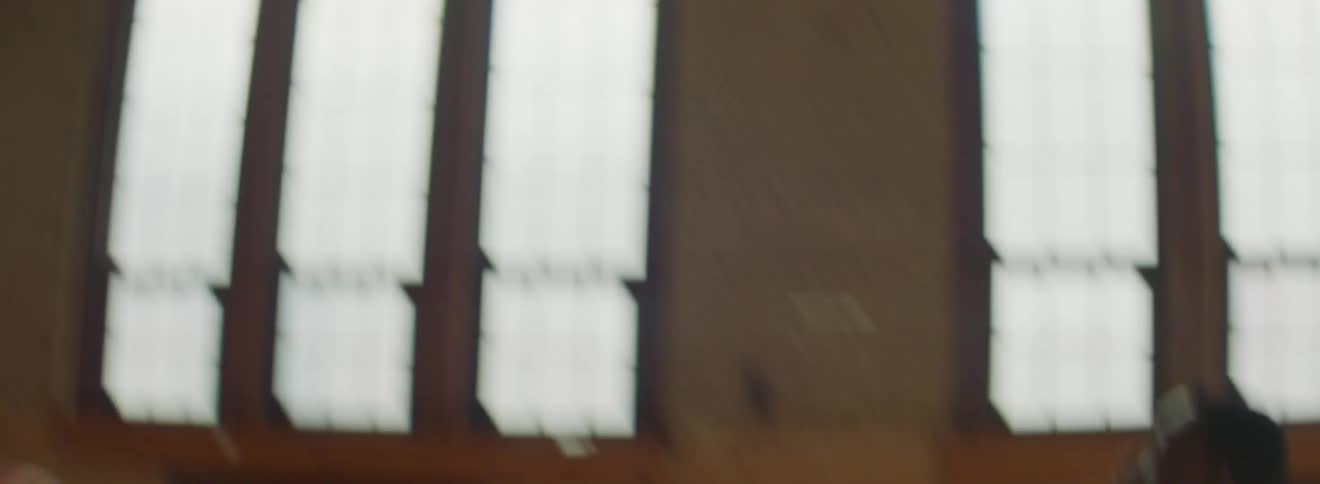 Men in a gym playing basketball with windows in the background