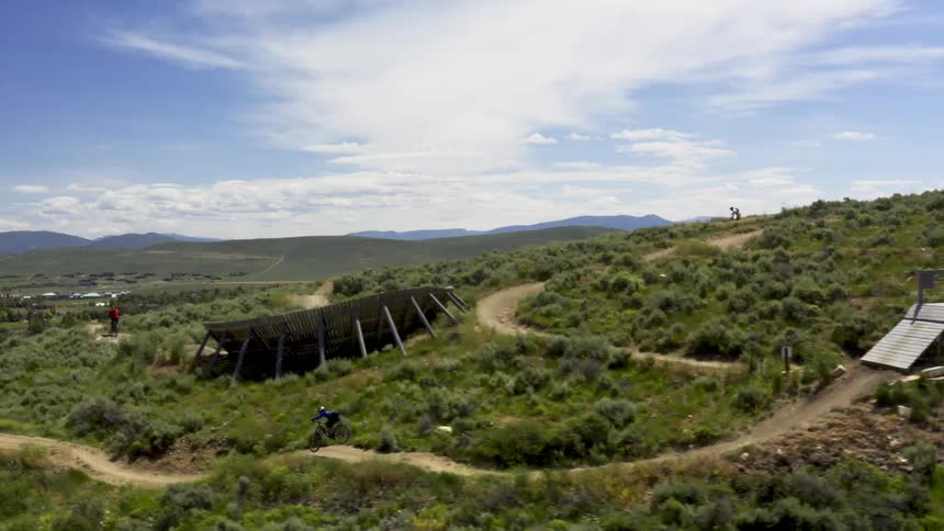 An aerial view of a bicyclist going over jumps on a dirt bike path
