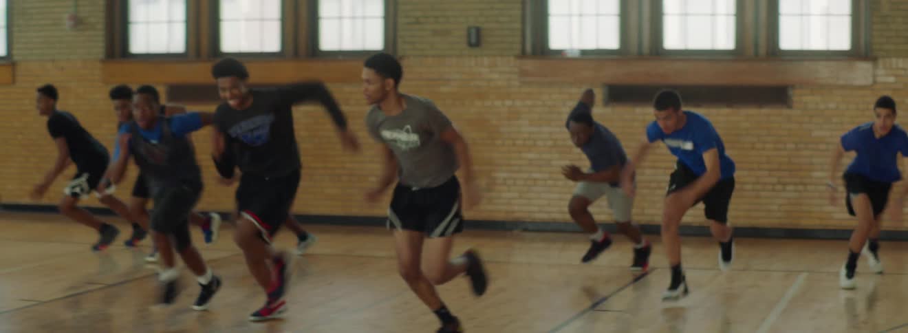A group of young men doing sprinting drills in a gymnasium during the day