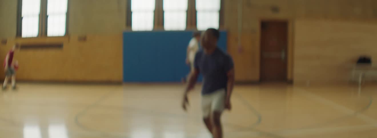 Men in a gym dribbling passing and shooting basketballs