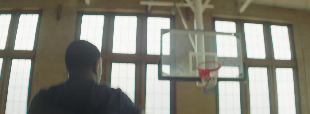 Black basketball player with a black t shirt shoots a basketball in the basketball court
