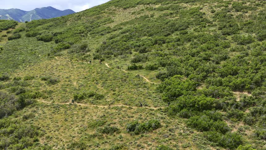 People descend down the trail on a mountain on bicycles