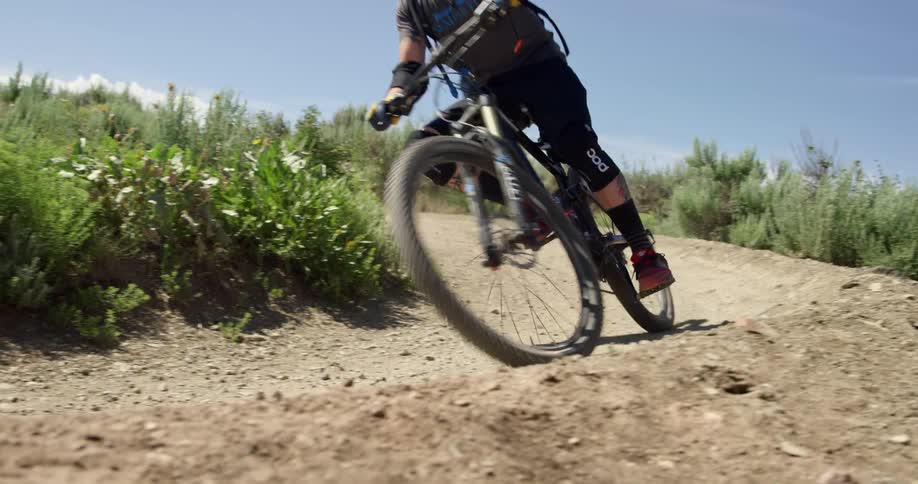 A man is biking outdoors on a gravel road