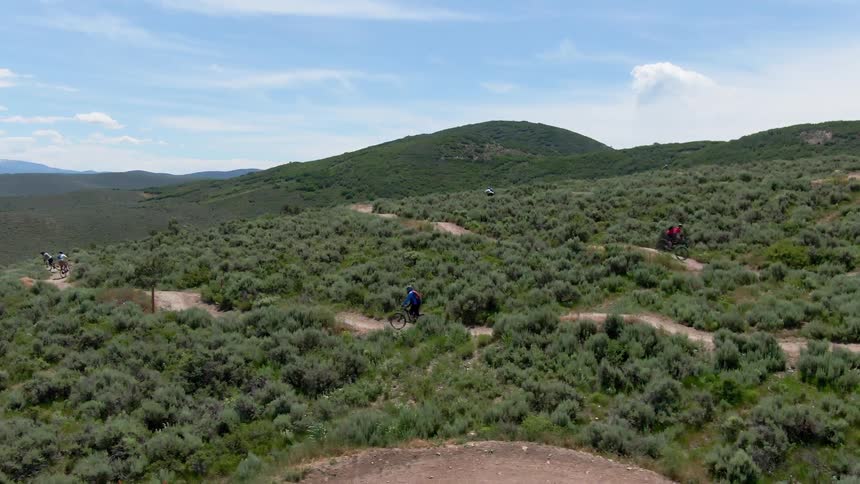 Aerial view of cyclist cycling on winding tracks in hills