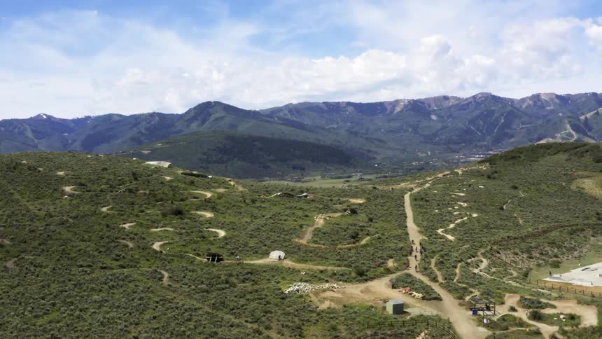 People bike ride and walk on curving looping trails with a mountain ridge behind