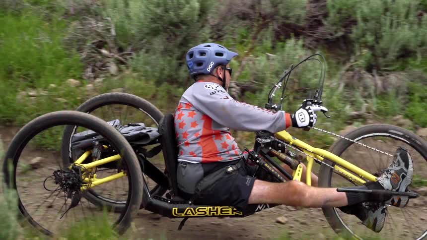 Disabled man rides a tricycle on a dirt trail with other bicycles