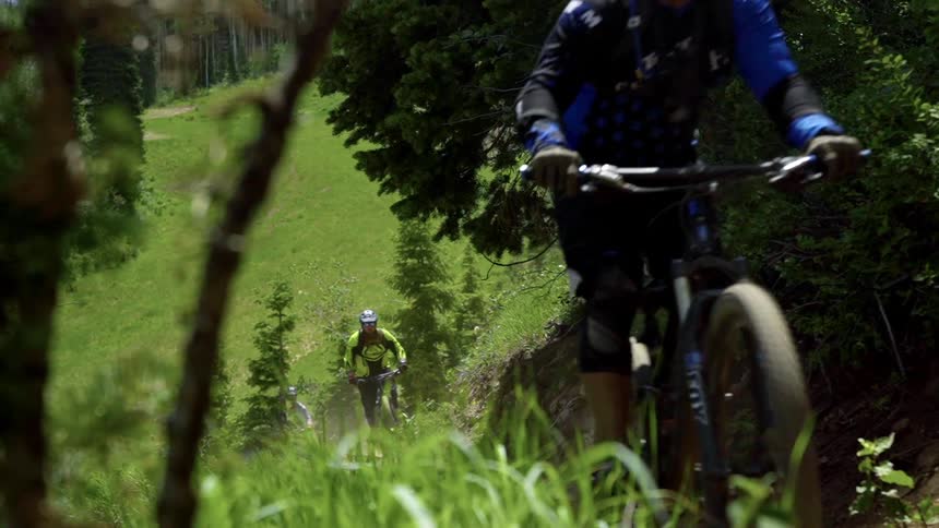 A trio of cyclist climb a dirt path up a hill using electric mountain bikes