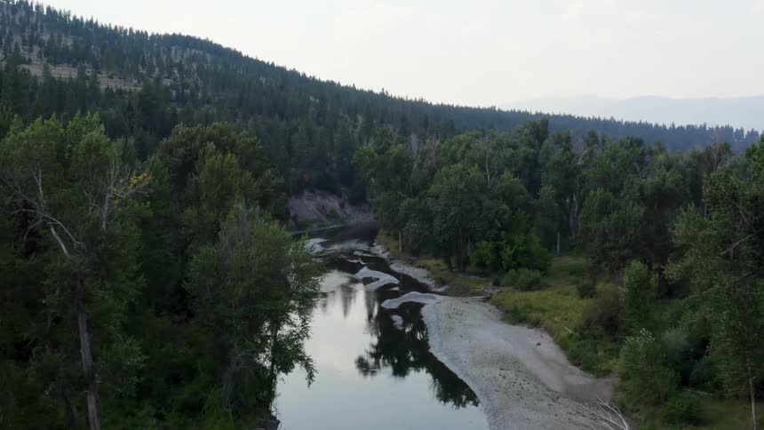 A river with trees and hills the sky and clouds in the background