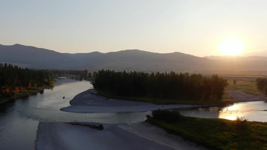 A river flows a long a snowy bank as the sun sets