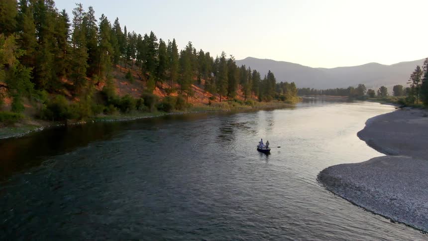 People row in the river by the hills