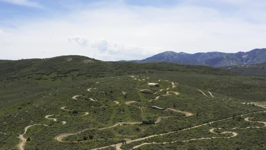 A dirt road obstacle with bikes with mountains the sky and clouds in the background