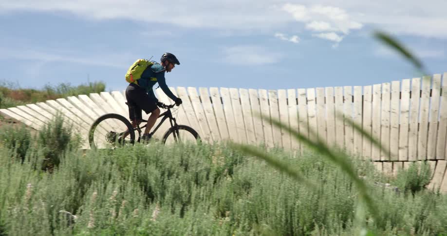 A man rides a mountain bike off road near a wooden ramp