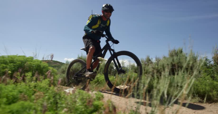 A man rides over a hill on his mountain bike