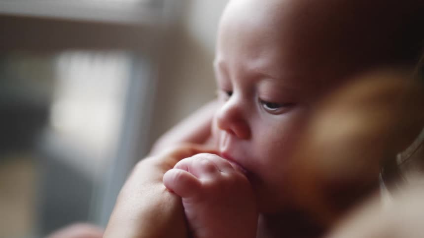 A person rocks a baby in their arms
