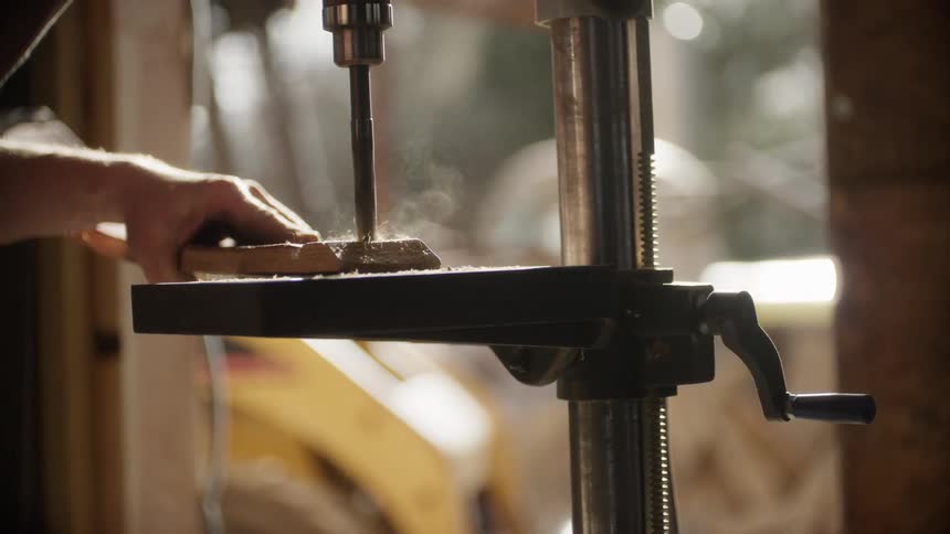 A person is using a drill to cut a hole in wood