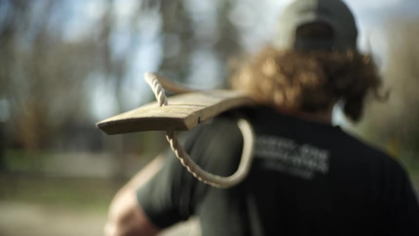 A man is walking to the forest carrying a board