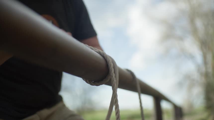 A man loops a rope around a post and ties it off