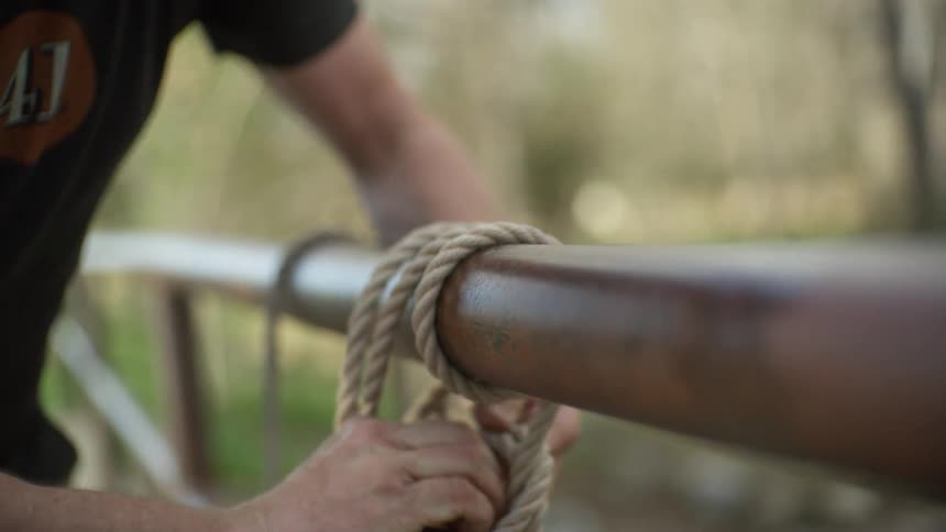 A man ties a rope on a railing