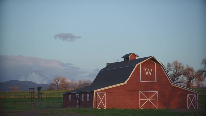 A large barn in field near a road in the countryside