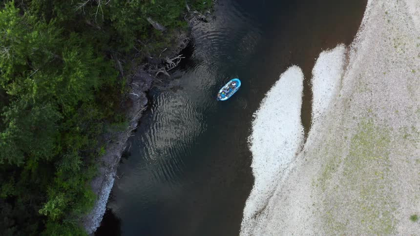Inflatable raft floats down the river next to the forest