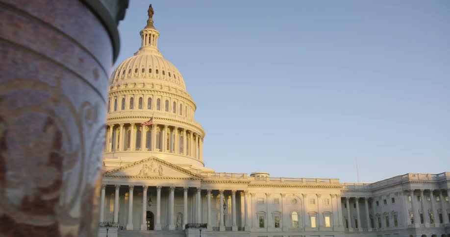 The capital building with an american flag in front and the sky in the background