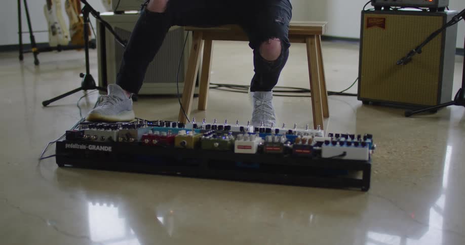 Musician uses a rack of guitar pedals on a studio