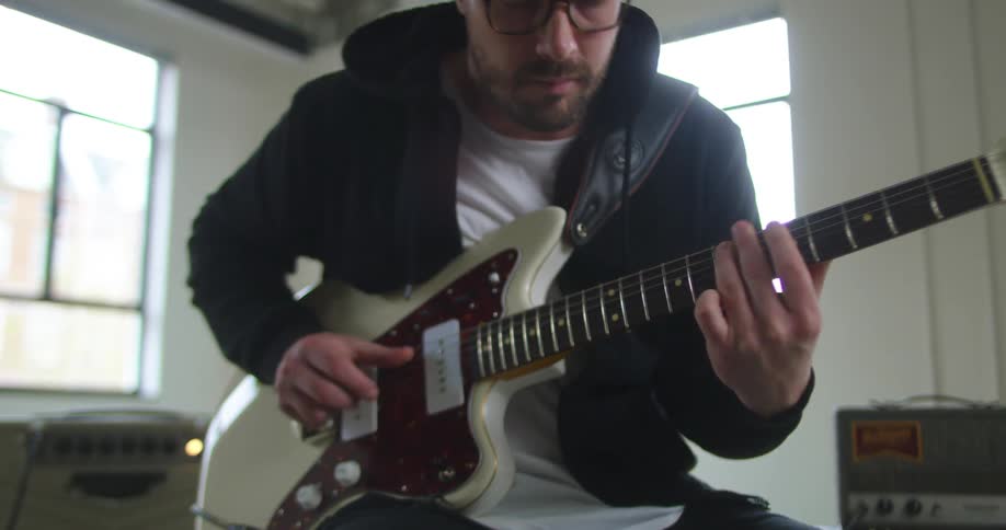 A man is playing the guitar in a room