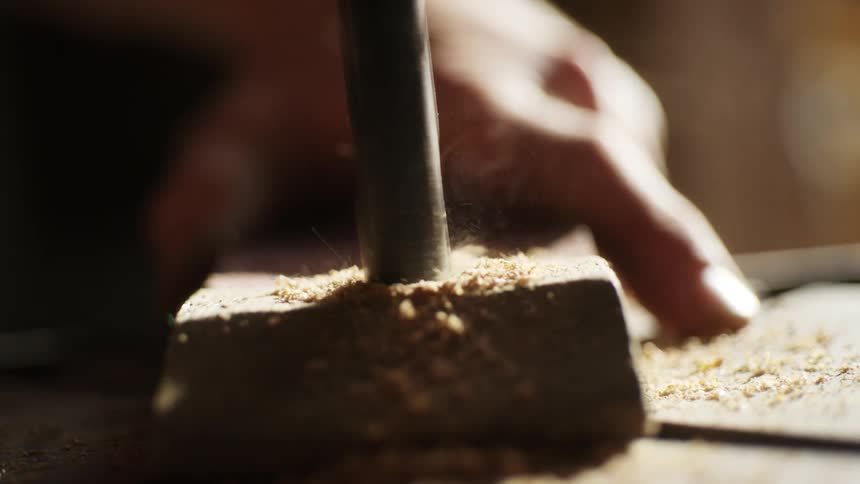 A person drills through a wooden board