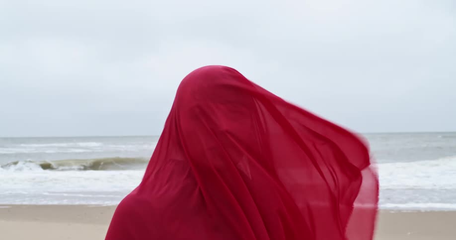 A woman is standing outdoors by the beach