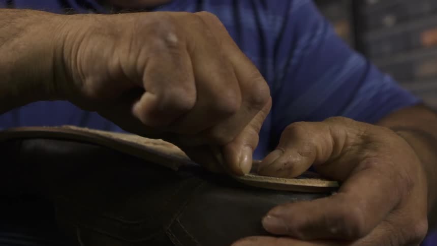 A man glues leather to the bottom of a shoe